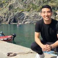 Daniel Kang posing in front of a body of water in France