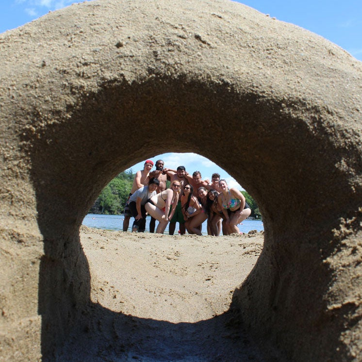 Kids pose behind a sand castle